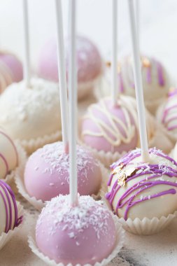 Beyaz mermer arka planda menekşe rengi kek çeşitleri ve farklı çikolata süslemeleri. Parlak serpiştirilmiş kekler.