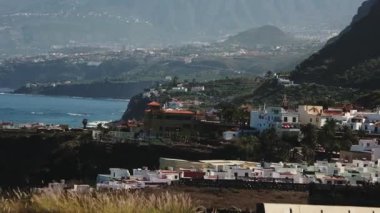 Güneşli yaz gününde otobandan çekilen tropikal kasabanın yavaş çekim görüntüleri. İspanya, Tenerife 'de okyanus kıyısındaki tropik tatil köyü manzarası. Seyahat konsepti