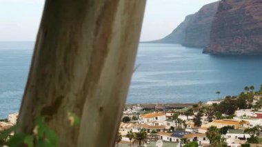 Los Gigantes kayalarında Puerto de Santiago 'dan Arial Manzara. Tenerife, Kanarya Adaları, İspanya. Yavaş çekim, tropikal şehrin görüntülerini ortaya çıkarıyor. Seyahat ve yaz tatili konsepti 