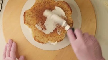 Pasta şefinin pasta tezgahını krem peynirle süslediği pasta poşeti ve spatulayla kapatmasını. Şekerlemecinin pastayı birleştirip süsleme süreci