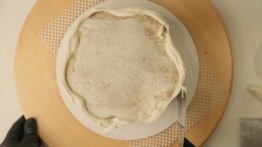 Pasta şefinin pasta tezgahını krem peynirle süslediği pasta poşeti ve spatulayla kapatmasını. Şekerlemecinin pastayı birleştirip süsleme süreci