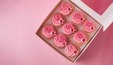 Krem şanti peyniriyle kaplanmış güzel çörekler. Pembe pastel arka planda bir kutu doğum günü pastası. Şenlikli tatlı teslimat konsepti