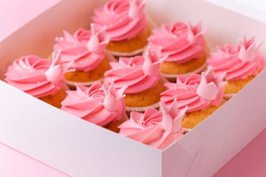 Pembe krem peynirli güzel kekler. Pembe pastel arka planda bir kutu doğum günü pastası. Şenlikli tatlı teslimat konsepti