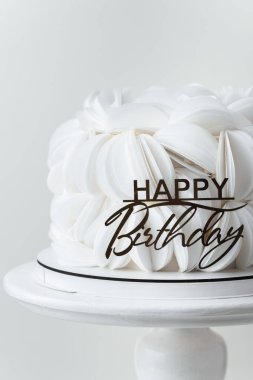 Beyaz yenilebilir kağıt yapraklarla kaplı doğum günü pastası ve altın doğum günü süsü ile süslenmiş. Beyaz arkaplan