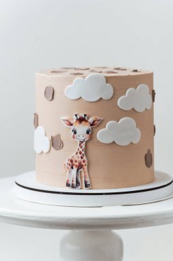 Beyaz arka planda yenilebilir zürafayla süslenmiş bej çikolatalı şirin Afrika tarzı doğum günü pastası..