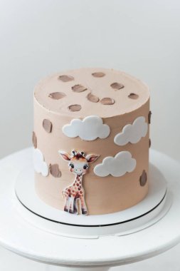 Beyaz arka planda yenilebilir zürafayla süslenmiş bej çikolatalı şirin Afrika tarzı doğum günü pastası..