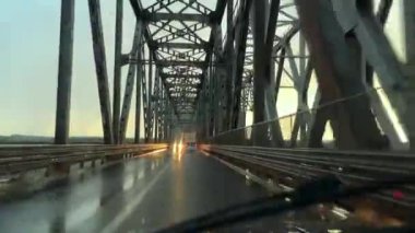 Köprüde çelik çerçeveli bir araba kullanmak. Gün batımında arabayla seyahat ederken arabanın ön camına çarpmış.