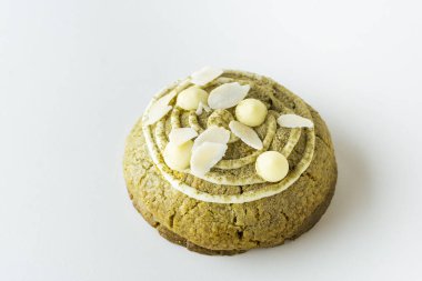 Badem gevreğiyle süslenmiş kibrit aromalı Amerikan çikolatalı kurabiyeleri ve beyaz arka plana saçılmış kibrit çay tozu. Düz yatıyordu