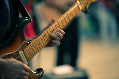 Gitar solosu çalarken sol eline odaklanmış bir gitaristin ellerinin detayları. Seçici odak.