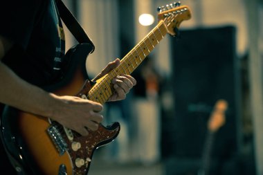 Bir şarkının performansı sırasında gitaristin ellerine odaklanan gitar. Seçici odak.