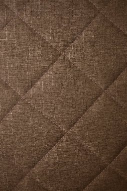 Kahverengi kumaşın yakın plan dikişleri görünür..