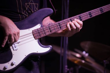 Canlı bir caz performansı sırasında bir basçının ellerinin basgitar üzerindeki detaylı görüntüsü, telleri ve enstrüman detaylarını vurguluyor..