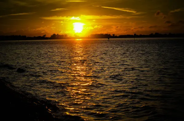 stock image Beautiful sunset over calm waters, with golden reflections and a silhouetted horizon.