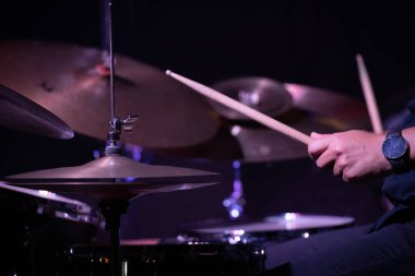 Hands playing the drums in a jazz performance, highlighting the rhythm and movement with a focus on the drumsticks.