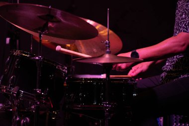 Davulcunun eli, bir caz konserinde bateri çalarken, siyah-beyaz yakalanır, ritim ve hareketi vurgular..