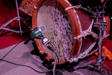 Close-up of a traditional drum and microphone setup on stage, focusing on the detailed texture of the drum skin and ropes.