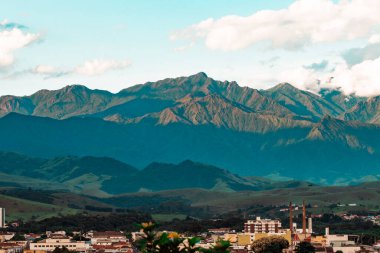 Stunning landscape showcasing mountain ranges under a clear blue sky, with a town nestled in the valley below. The scene captures the serene beauty of the mountainous region. clipart