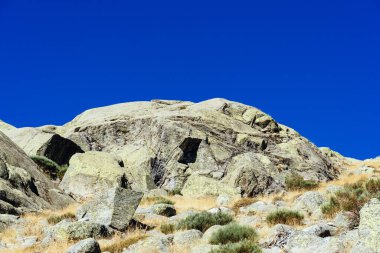 İspanya 'daki Gredos Park' ta sonbaharda mavi bir gökyüzünün altındaki bir çayır üzerindeki kayaların güzel manzarası.