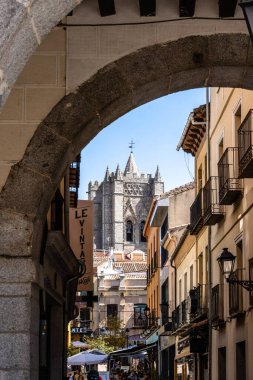 Avila, İspanya - 11 Eylül 2022: Arka planda Katedral Kulesi olan eski kasaba manzarası. Plaza del Mercado Chico ya da Small Arcade of the Plaza del Mercado Chico tarafından çerçevelenmiş katedralin görüntüsü