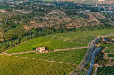 Haro, Spain - June 6, 2020: Vineyards and winery on the banks of the Ebro river next to the city of Haro. High angle view. Gorge of Conchas de Haro in La Rioja, Spain.