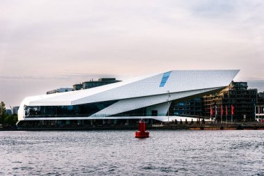 Amsterdam, Hollanda - 6 Mayıs 2022: IJ su yolu bankasının günbatımında manzara. Amsterdam Ufuk Çizgisi: Göz Filmleri Müzesi