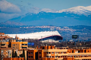 Madrid, İspanya - 12 Ocak 2022: Arkadaki kar dağlarına karşı Atletico de Madrid Metropolitano Stadyumu 'nun nefes kesici telefon lensleri manzarası. Turizm ve editör projeleri