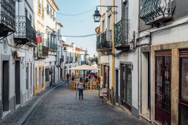 Evora, Portekiz - 29 Haziran 2022: Tipik beyaz yıkanmış balkonlu evleri olan eski bir kasabada sokak. Alentejo, Portekiz