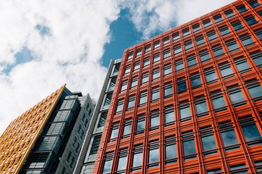 Londra, İngiltere - 27 Ağustos 2023: Londra 'daki modern ve renkli apartman ve ofis binalarının alçak açılı görünümü. Batı Yakası 'ndaki Merkez Saint Giles. Kopyalamak için beyaz bulutlu mavi gökyüzüne karşı görüntüle.