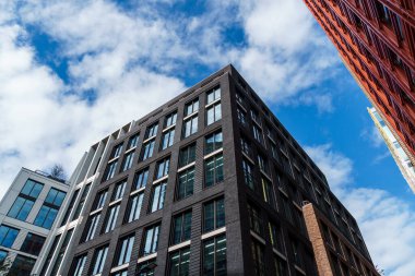 Londra, İngiltere - 27 Ağustos 2023: Londra 'daki modern ve renkli apartman ve ofis binalarının alçak açılı görünümü. Batı Yakası 'ndaki Merkez Saint Giles. Kopyalamak için beyaz bulutlu mavi gökyüzüne karşı görüntüle.