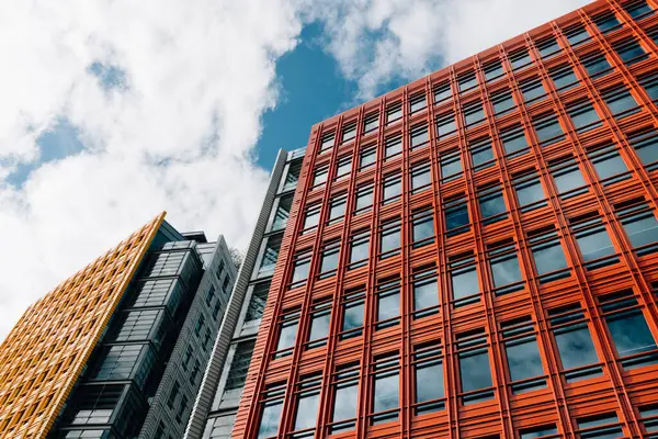 stock image London, UK - August 27, 2023: Low angle view of modern and colorful apartment and office buildings in the City of London. Central Saint Giles in the West End. View against blue sky with white clouds with space for copy.