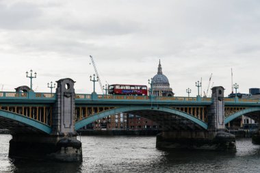 LONDON, İngiltere - 26 Ağustos 2023: Londra 'daki St. Paul Katedrali' ne karşı Southwark Köprüsü üzerinden geçen Kızıl Otobüs. Alacakaranlıkta görüntüle