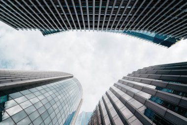 Londra, İngiltere - 25 Ağustos 2023: Londra 'daki modern ofis binalarının düşük açılı görüntüsü ve perde önü yansımaları. Beyaz bulutlu mavi gökyüzüne bak. İş konsepti