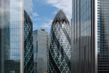Londra, İngiltere - 25 Ağustos 2023: Londra 'daki modern ticari gökdelenler ofis binaları ve perde önlerindeki yansımalar. Beyaz bulutlu mavi gökyüzüne bak
