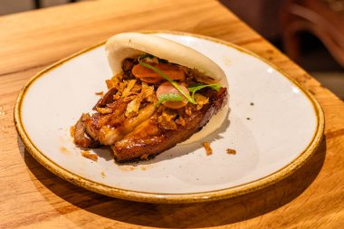 Kıtır soğan ve kişniş ile düşük sıcaklıkta kızarmış domuz pastırmalı bao. Füzyon mutfağı tapa