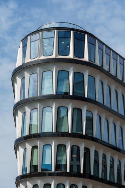 Londra, İngiltere - 25 Ağustos 2023: Londra 'daki modern ofis binası. Düşük açı beyaz bulutlu mavi gökyüzüne karşı.