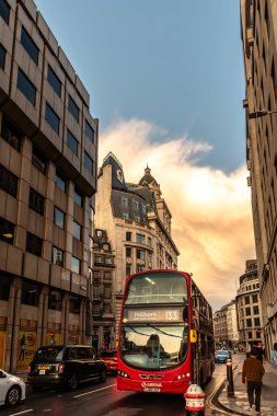 Londra, İngiltere - 25 Ağustos 2023: Çift katlı kırmızı otobüs alacakaranlıkta Cannon Caddesi 'nde hızlanıyor