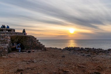 Ciutadella, İspanya - 13 Mayıs 2024: Günbatımında Punta Nati Deniz Feneri 'nde gitar çalan Busker