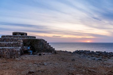 Ciutadella, İspanya - 13 Mayıs 2024: Günbatımında Punta Nati Deniz Feneri 'nde gitar çalan Busker