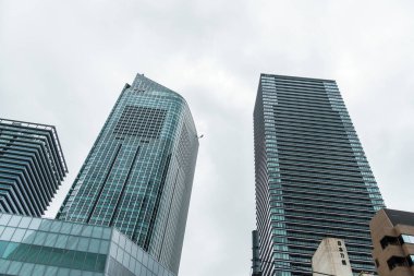 Tokyo, Japonya - 08 Ağustos 2024: Toranomon Hills bölgesinde gökyüzüne karşı ofis binalarının alçak açılı görünümü.