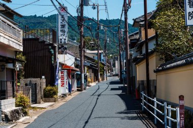 Nara, Japonya - 14 Ağustos 2024: Japonya 'nın Nara kentinde aile evleri ve yerel dükkanlarla dolu geleneksel dar bir cadde. Sahne, yukarıdaki elektrik kablolarıyla mahallenin günlük yaşamını yakalıyor ve bu kentsel arazinin cazibesini arttırıyor.