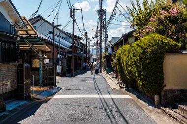 Nara, Japonya - 14 Ağustos 2024: Japonya 'nın Nara kentinde aile evleri ve yerel dükkanlarla dolu geleneksel dar bir cadde. Sahne, yukarıdaki elektrik kablolarıyla mahallenin günlük yaşamını yakalıyor ve bu kentsel arazinin cazibesini arttırıyor.