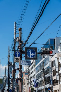 Nara, Japonya - 14 Ağustos 2024: Japonya 'nın Nara kentinde trafik ışıkları, yol işaretleri ve gökyüzünde çapraz elektrik kabloları bulunan hareketli bir kavşak.