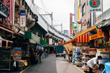 Tokyo, Japonya - 6 Ağustos 2024: Ueno, Tokyo 'da canlı bir sokak pazarı olan Ameyoko, hareketli dükkanlar, gıda tezgahları ve yerel ürünler sunarak Japon sokak ticaretinin canlı özünü yakalıyor.