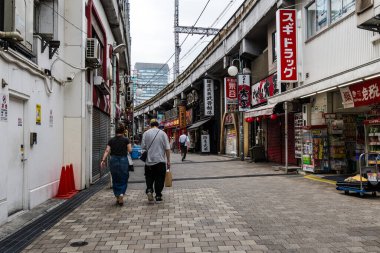 Tokyo, Japonya - 6 Ağustos 2024: Ueno, Tokyo 'da canlı bir sokak pazarı olan Ameyoko, hareketli dükkanlar, gıda tezgahları ve yerel ürünler sunarak Japon sokak ticaretinin canlı özünü yakalıyor.