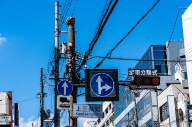 Nara, Japonya - 14 Ağustos 2024: Japonya 'nın Nara kentinde trafik ışıkları, yol işaretleri ve gökyüzünde çapraz elektrik kabloları bulunan hareketli bir kavşak.