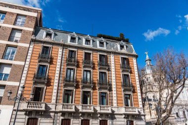 Madrid, İspanya 'da klasik mimari, Almudena Katedrali yakınlarındaki canlı mavi gökyüzüne karşı süslü balkonları olan binalar..