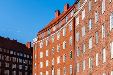 Helsinki 'de güneşli bir günde klasik tuğla mimari manzarası, kendine özgü kırmızı kiremitli çatıları ve simetrik pencere tasarımlarını sergiliyor..