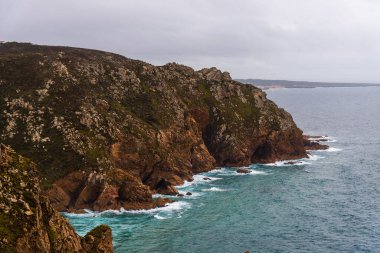 Portekiz 'deki Cape Roca' daki kayalıkların dramatik bir görüntüsü. Dalgaların bulutlu bir günde kayalara çarptığı yer..
