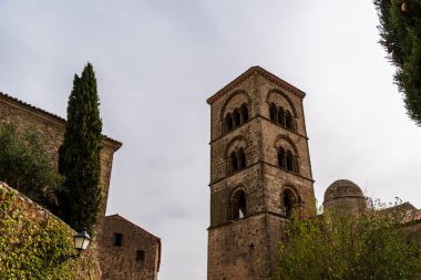 Yukarıya bakan bir manzara, Trujillo Extremadura 'nın mimarisini yakalıyor, parlak gökyüzüne karşı bir çan kulesi ve taş binalar sergiliyor..