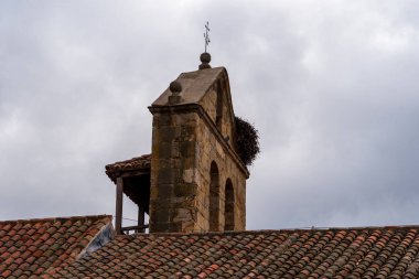 İspanya, Montejo 'da bulutlu bir gökyüzünün altında leylek yuvası olan bir kilise çan kulesinin alçak açılı görüntüsü..